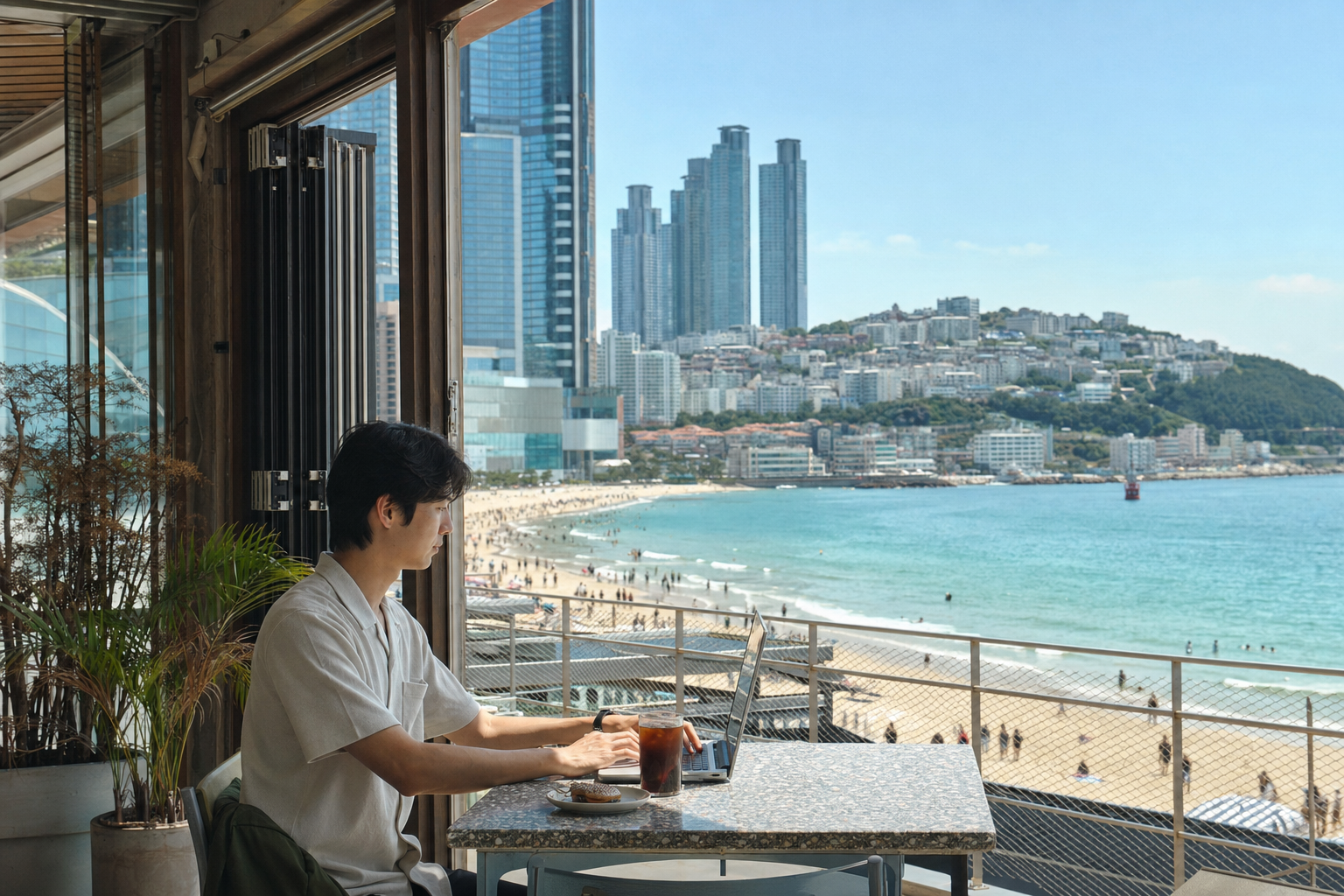 부산 바다 전망 카페에서 노트북으로 일하는 여행자
